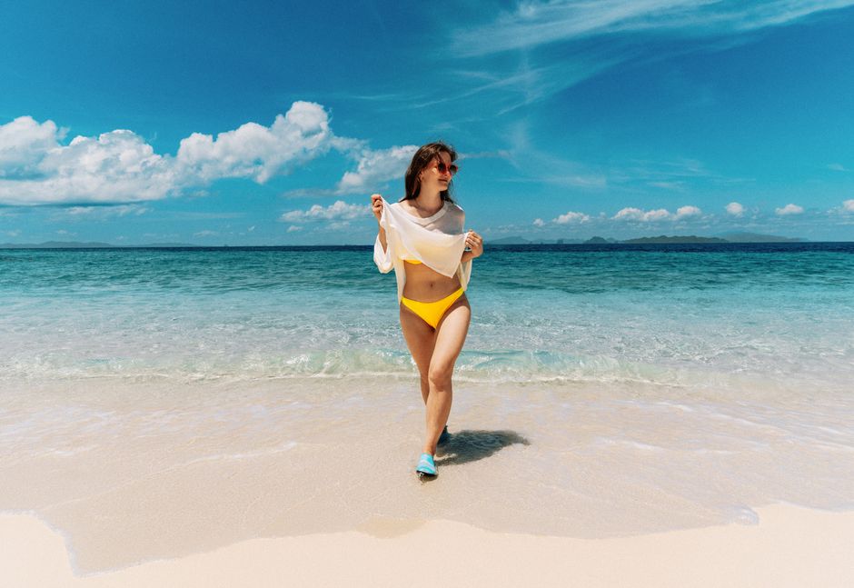Woman in yellow bikini on Ao Nang Beach with clear blue water and bright sky.