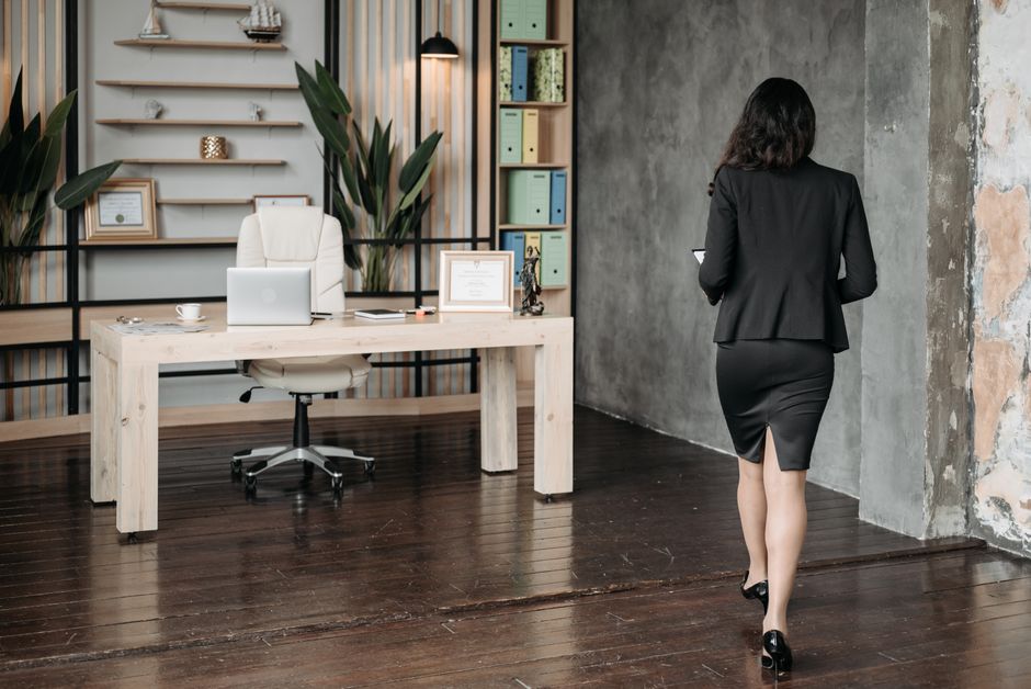 Businesswoman in corporate attire walking in elegant modern office space.