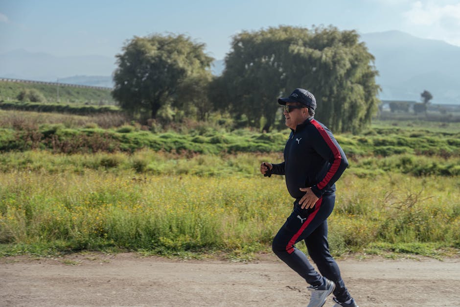 A man in sportswear jogging on a scenic rural path during the day.