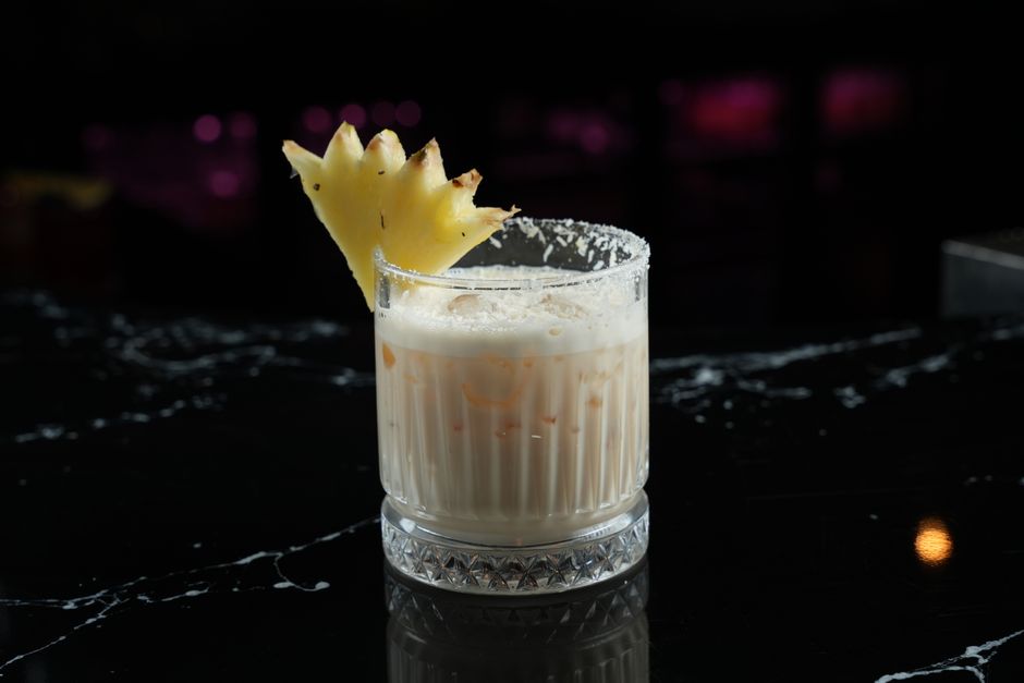 Delicious pina colada cocktail with a fresh pineapple slice on a glass, perfect for summer.