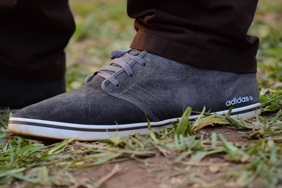 Detailed close-up of a suede Adidas shoe on grass, perfect for fashion and lifestyle themes.