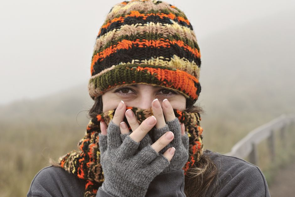 A woman wears knitted hat and gloves in a foggy Ecuadorian landscape, capturing a cozy winter feel.