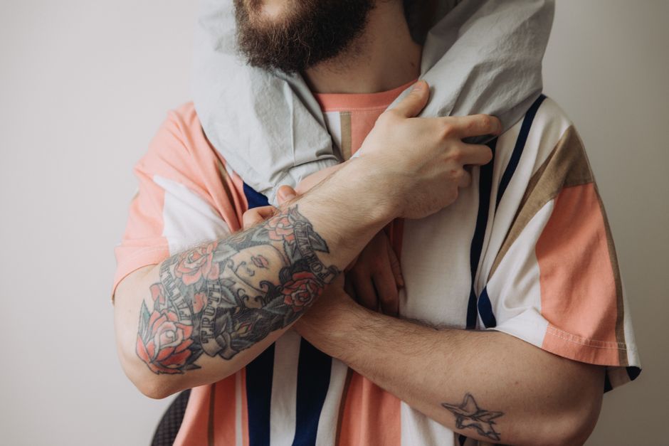 Close-up of tattooed man in patterned t-shirt embracing with a personal touch.