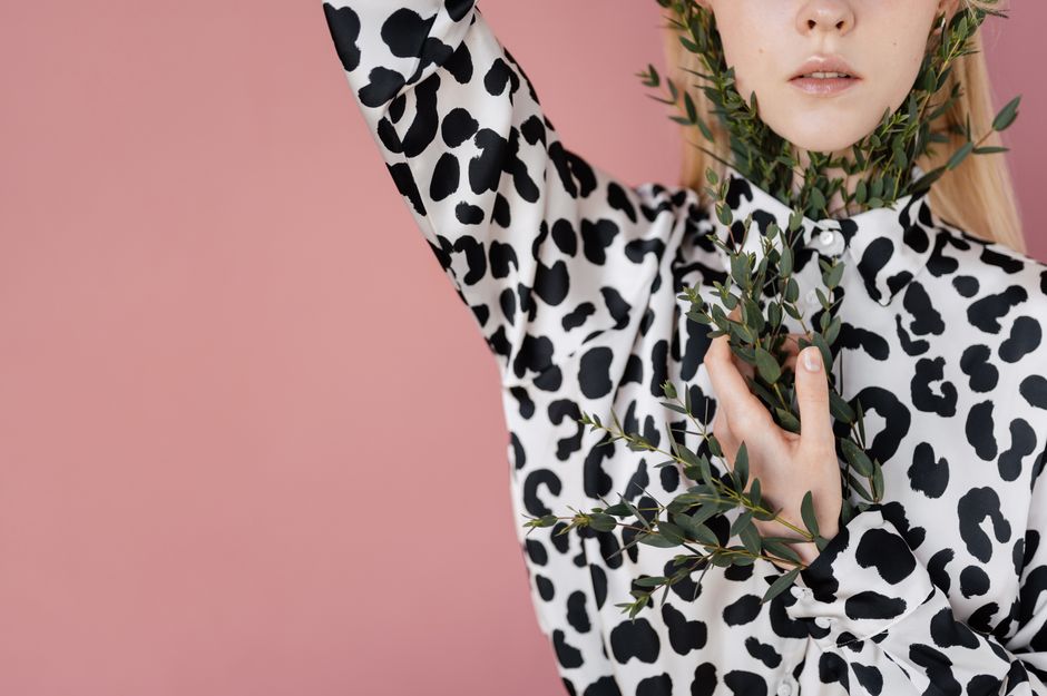 Stylized fashion portrait featuring a woman in an animal print shirt with leafy branches.