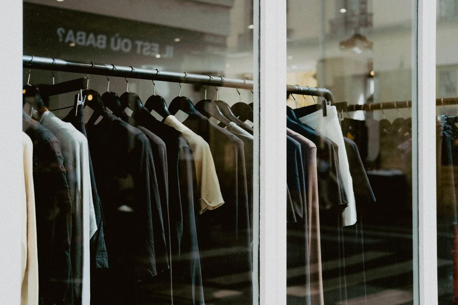 Close-up of clothing on hangers inside a fashion store window.