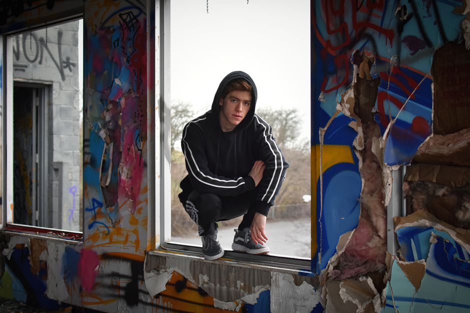 Caucasian man crouches in a graffiti-filled abandoned building, Nashville.