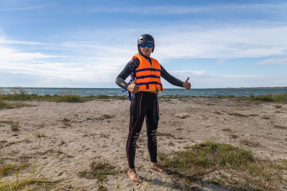 Man ready for water sport on beach in safety gear. Outdoor adventure awaits.