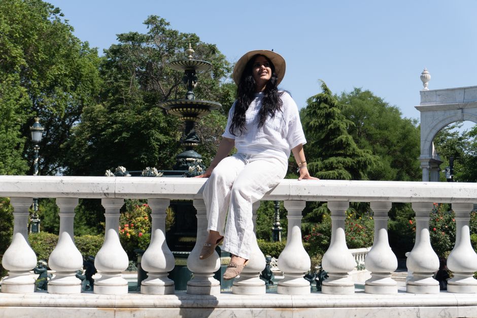 Woman enjoying a sunny day in a park in Baku, Azerbaijan, sitting on a marble railing.